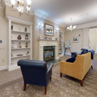 A cozy living room with elegant furniture, a fireplace, and decorative bookshelves.
