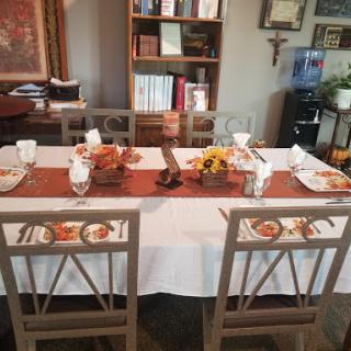 A beautifully arranged dining table ready for a gathering, featuring autumn decorations and an inviting atmosphere.