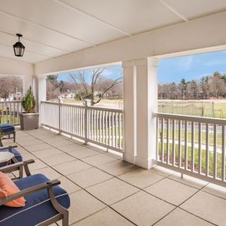 A spacious porch with comfortable seating overlooks a scenic landscape.