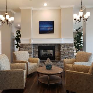 A cozy living room with a stone fireplace, surrounded by comfortable armchairs and elegant chandeliers.