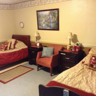 A cozy bedroom with two beds, an armchair, and decorative elements.