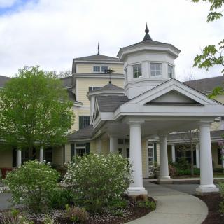 A picturesque view of a traditional styled building with a grand entrance and surrounding greenery.