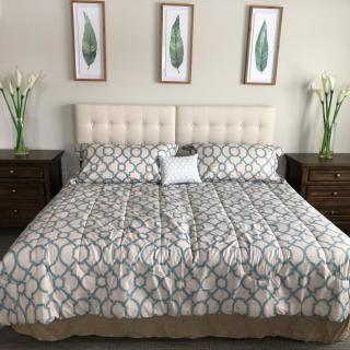 A neatly arranged bedroom featuring a large bed with patterned bedding, flanked by nightstands and decorative artwork on the wall.