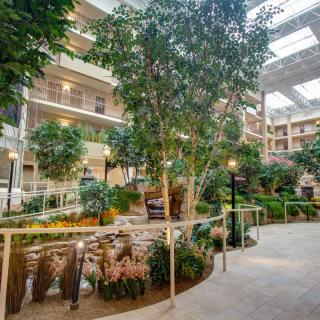 A spacious indoor atrium filled with lush greenery and a walking path under natural light.