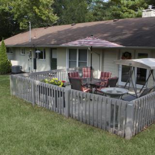 A cozy backyard patio with outdoor furniture and an umbrella, enclosed by a wooden fence.