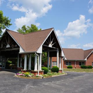 An entrance to a building with landscaped surroundings under a partly cloudy sky.