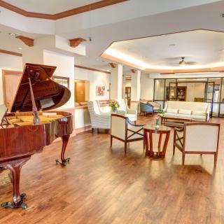 A spacious living room featuring a grand piano and elegant furniture on a wooden floor.