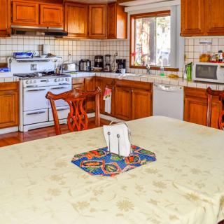 A cozy kitchen featuring wooden cabinets, a dining table with a colorful mat, and various kitchen appliances.