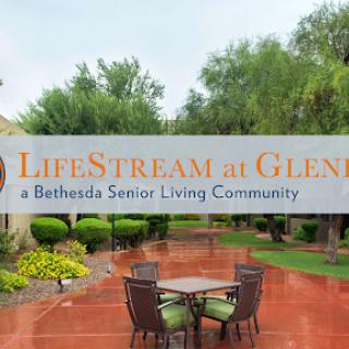 Entrance to LifeStream at Glen, a senior living community, featuring outdoor seating and lush landscaping.