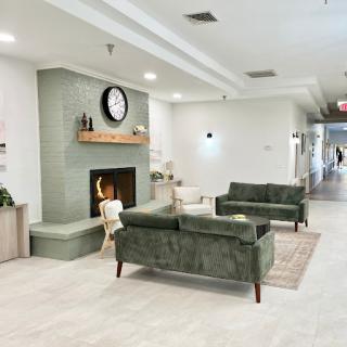 A cozy and modern lobby featuring green couches and a fireplace, ideal for relaxation.