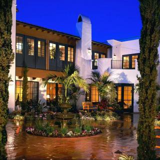 A Mediterranean-style house with a beautifully landscaped courtyard illuminated at night.