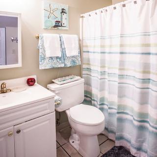 A clean and tidy bathroom with a white sink, toilet, striped shower curtain, and decorative elements.