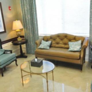 A cozy living room with elegant furniture including a sofa, chairs, and a round glass table.
