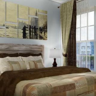 A cozy bedroom with stylish bedding and artwork on the wall.