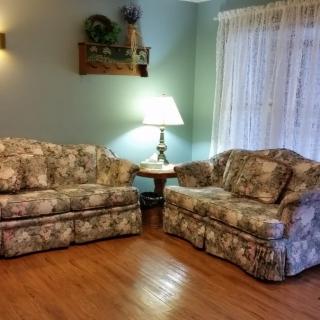 A cozy living room with floral patterned couches and a lamp on a side table.