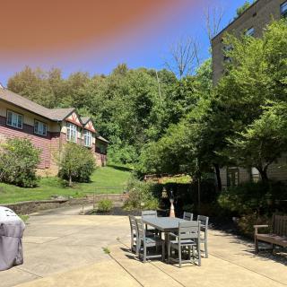 A sunny outdoor patio area with furniture surrounded by trees and buildings.