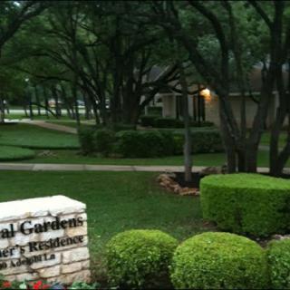 A serene garden view featuring a residence sign and manicured bushes.