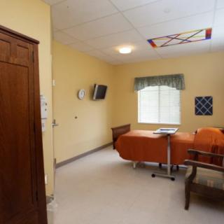 A hospital room with a bed, television, and window.