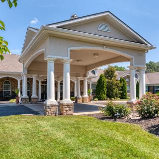 Elegant building entrance with landscaped garden and columns.
