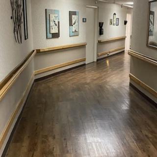 A long hallway with wooden flooring and artwork on the walls.