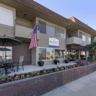 An apartment building with an American flag, outdoor seating, and a landscaped area with flowers.