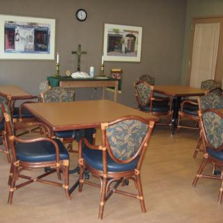 A room with tables and chairs, featuring religious decor.