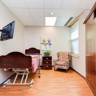 A well-lit patient room featuring a hospital bed, an armchair, and modern furnishings.