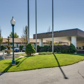 Entrance to a hotel with flagpoles and landscaped surroundings.