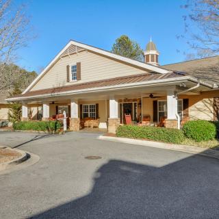 A large residential building with a porch, photographed during the daytime.
