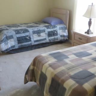 A bedroom with two twin beds and a nightstand with a lamp.