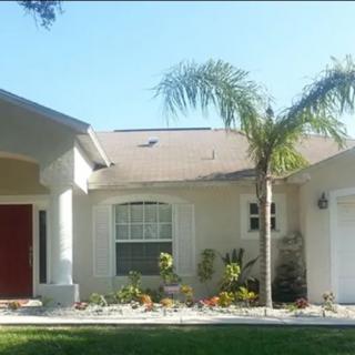 A suburban house with a well-maintained front yard featuring palm trees and garden landscaping.