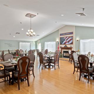 A spacious dining area with elegant tables and chairs, featuring a fireplace and flag-themed artwork.