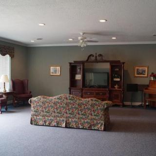 A spacious living room with a patterned sofa, television console, and classic furniture.