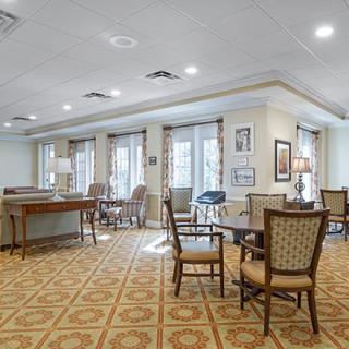 A spacious and well-lit seating area with tables and chairs arranged on a patterned carpet.