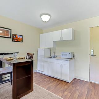 A cozy kitchenette with dining table, cabinets, and appliances.