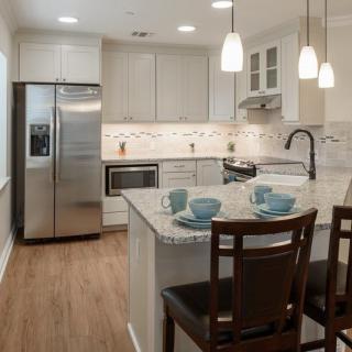 A modern kitchen featuring an island with seating, stainless steel appliances, and pendant lighting.