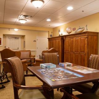 A cozy room with a table set up for board games, surrounded by wooden chairs and warm lighting.