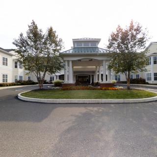 Front view of a building with landscaped entrance and surrounding trees.