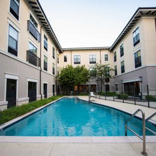 A modern apartment complex featuring a central outdoor swimming pool.