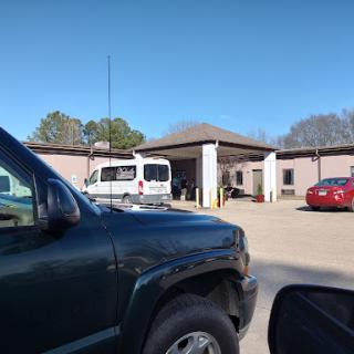 A view of a parking lot with various vehicles and a building in the background on a clear day.