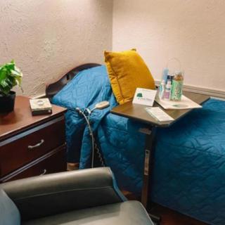 A cozy hospital room with a bed, side table, and a comfortable chair.