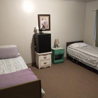A simple bedroom with two beds, two nightstands, and a piece of artwork on the wall.