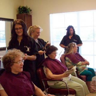 Hairstylists attending to elderly women in a salon.