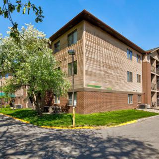 A residential apartment building with surrounding greenery on a sunny day.
