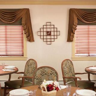 A cozy dining room setup with elegant chairs, tables, and decorative window treatments.