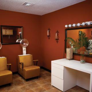 A cozy salon interior with comfortable chairs and hair dryers, featuring elegant wall mirrors and warm decor.