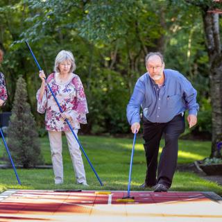 A group of seniors enjoying a game of shuffleboard in a lush garden setting.
