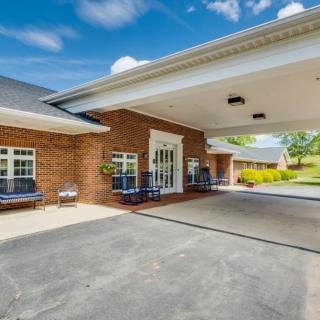 A brick building with a covered entrance and driveway on a sunny day.