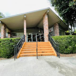 A modern building entrance featuring a set of wooden stairs surrounded by lush greenery.