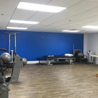 A spacious gym interior with exercise equipment and a vibrant blue wall.